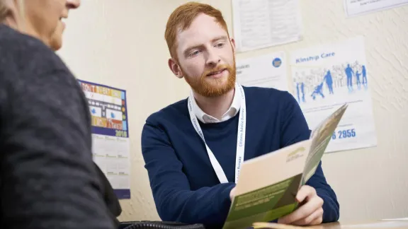 A photo of a man holding a file explaining it to another person