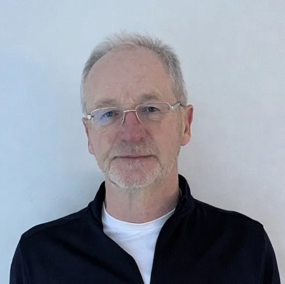 Male member of the board with grey hair and glasses.