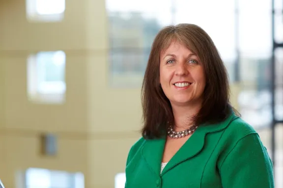 Female member of the board with brown hair with an office block in the background